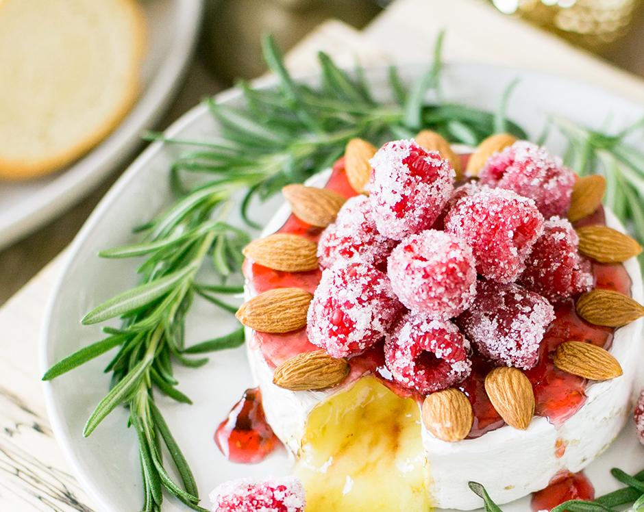 Baked brie topped with candied raspberries, almond, and glazed with Ravens Nest raspberry jalapeno jam