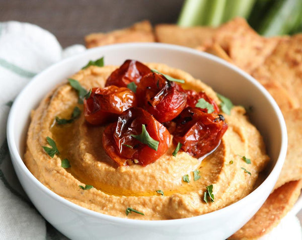 Roasted tomato hummus made with Raven's Nest garden party mix topped with blistered cherry tomatoes and served with pita chips