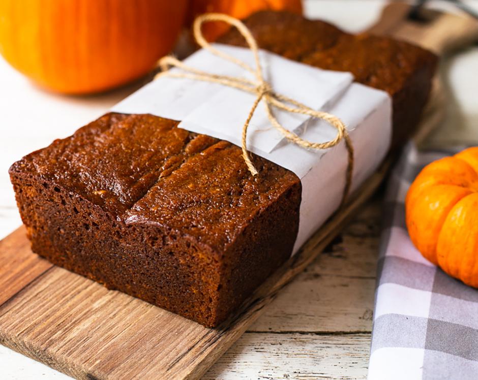 Pumpkin bread with cream cheese filling made with Raven's Nest pumpkin butter and mulling spice, wrapped in butcher paper and tied with a string surrounded by fresh fall pumpkins