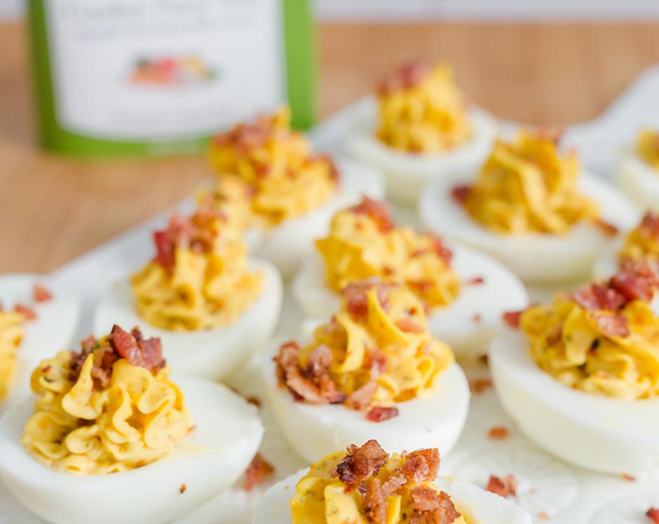Southern style deviled eggs appetizer made with Raven's Nest garden party dip mix and topped with crumbled bacon